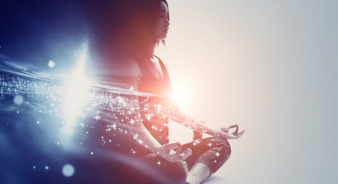 Person meditating with a bright light and sparkling energy indicating enlightenment.