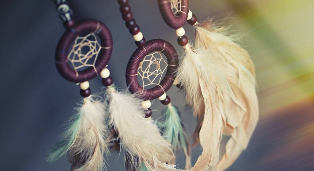 Dreamcatcher with feathers against a blurred background.