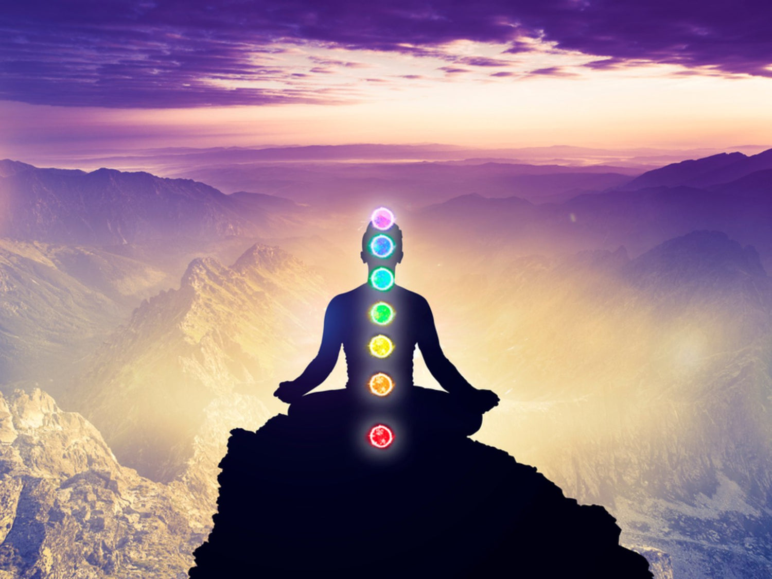 A silhouetted figure in lotus pose on a mountain at sunrise, with glowing chakras suggesting the flow of energy and potential for well-being offered by distant healing treatments in a peaceful setting.
