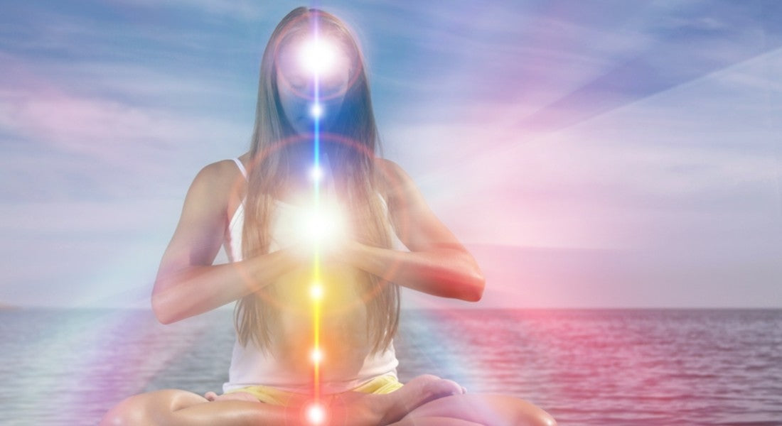 Person meditating with energy points highlighted against a beach background.