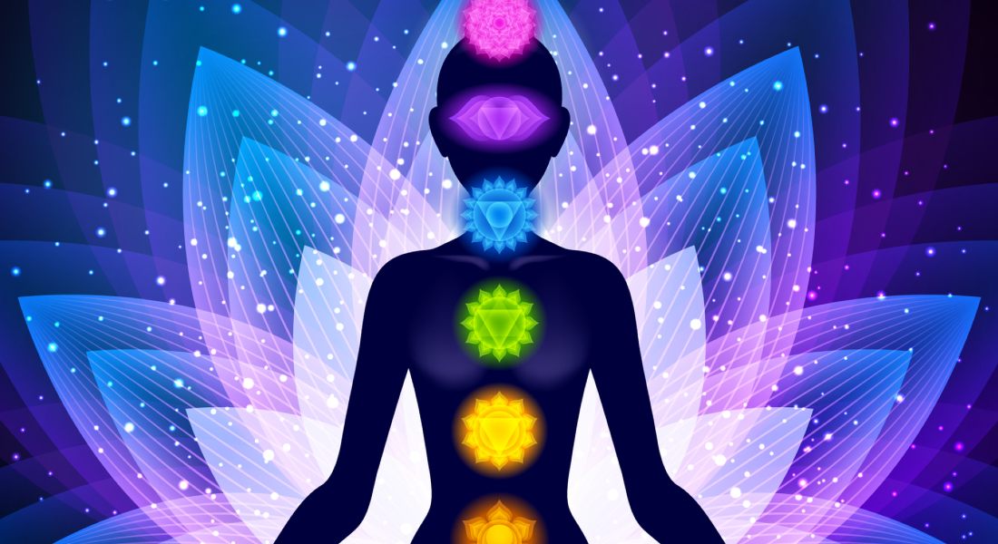 Silhouette of a person with chakras on a starry lotus background.