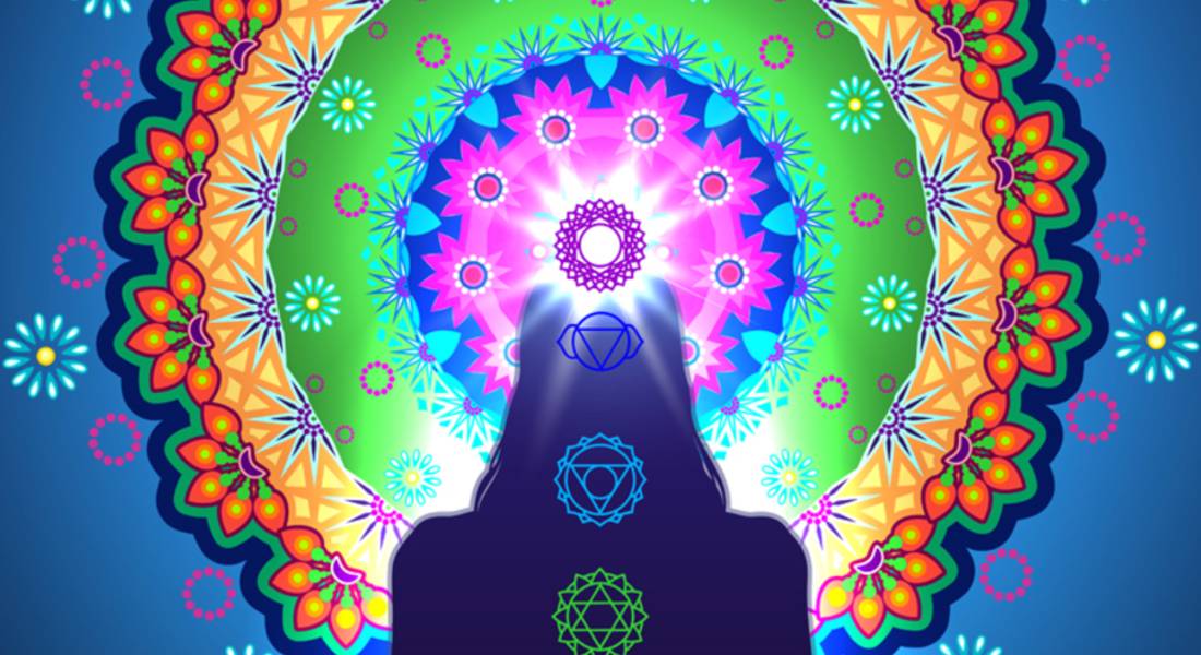 Silhouette of a person with chakra symbols and a colourful mandala design on a blue background.