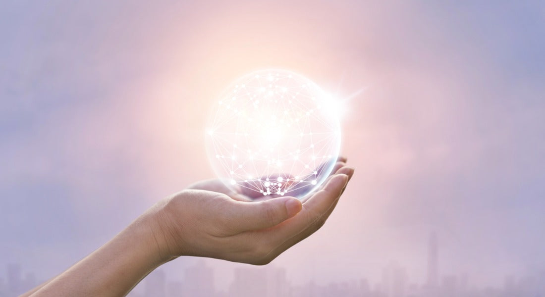 Hands holding a radiant glowing orb of light against a glowing pink background.
