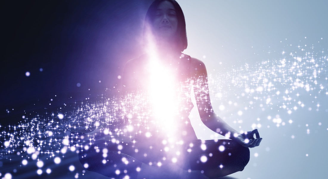 Person meditating with a glowing effect on a dark background.