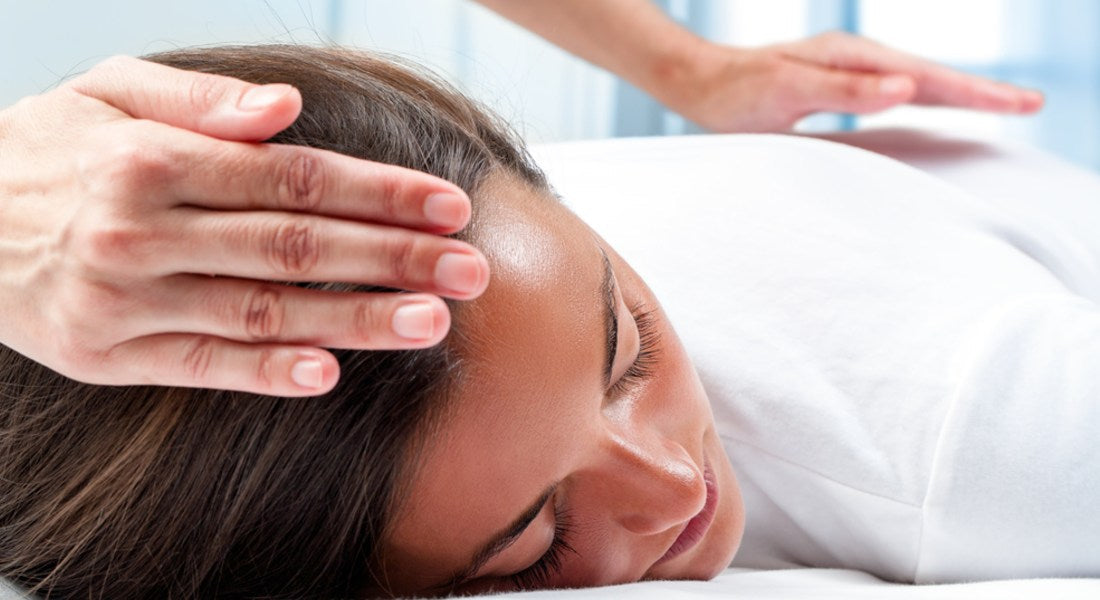 Person receiving Reiki healing with hands on a blurred background.