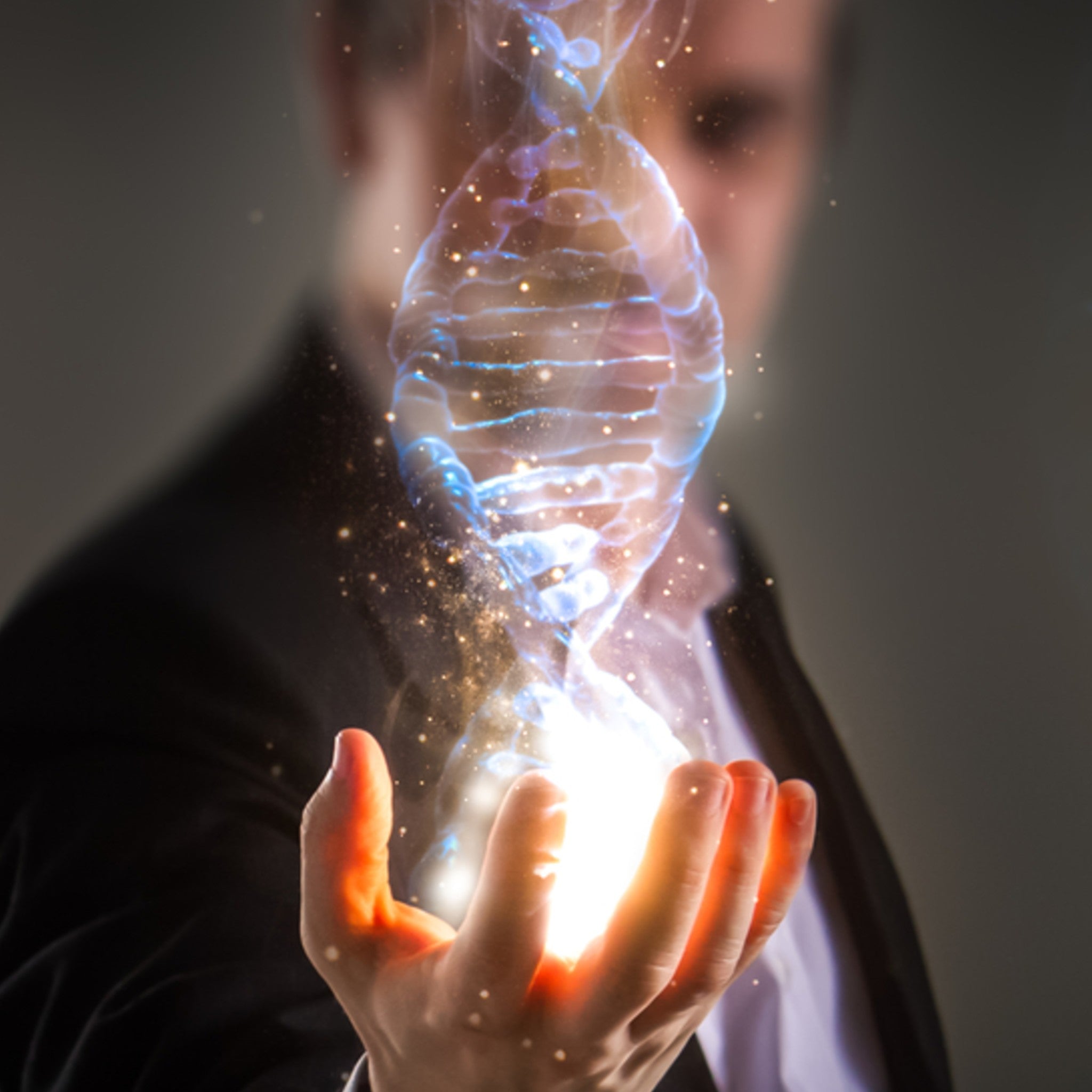 A person's hand cupping a brilliant, glowing light from which a shimmering blue and gold double helix DNA strand emerges.