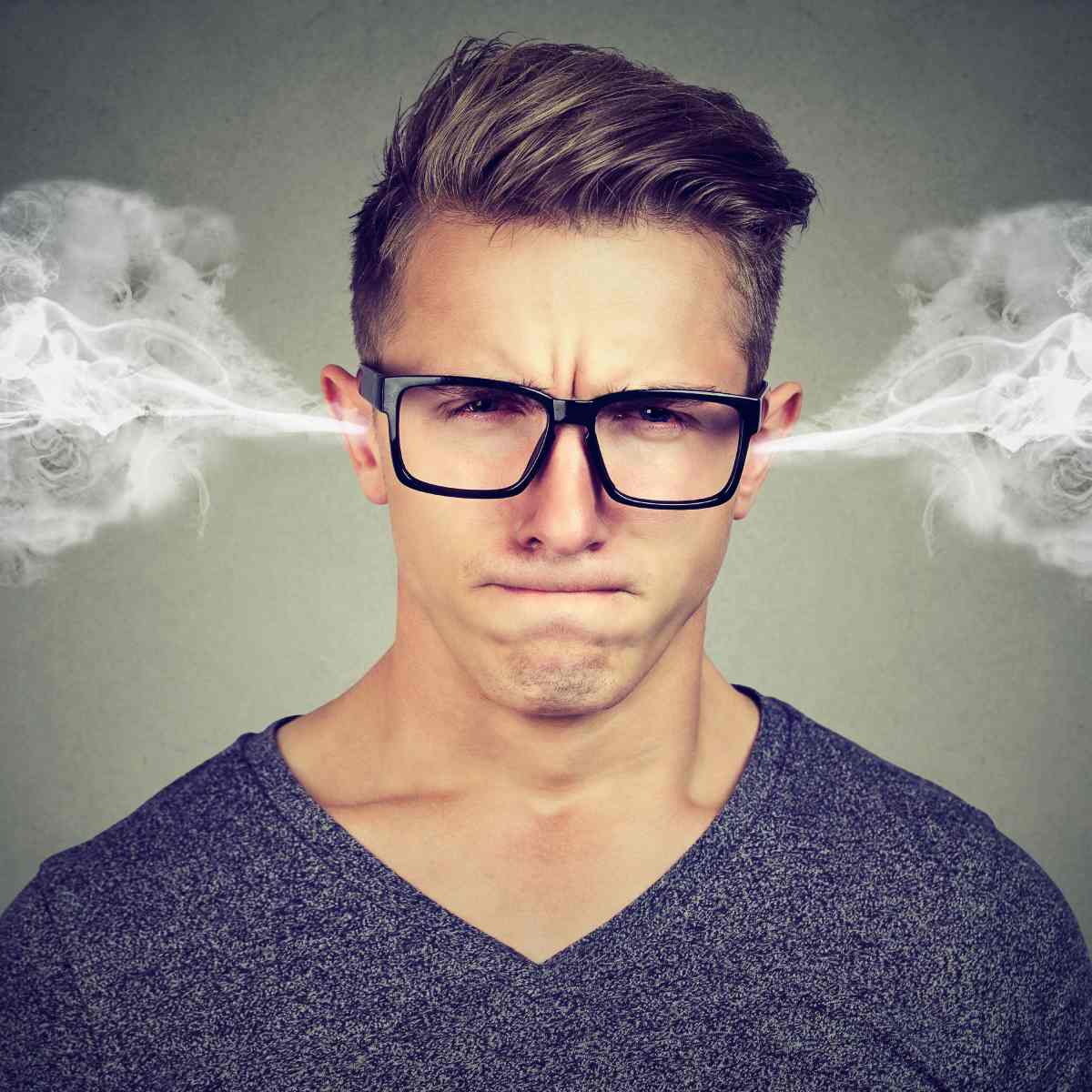 Angry young man with glasses and steam blowing out of his ears.