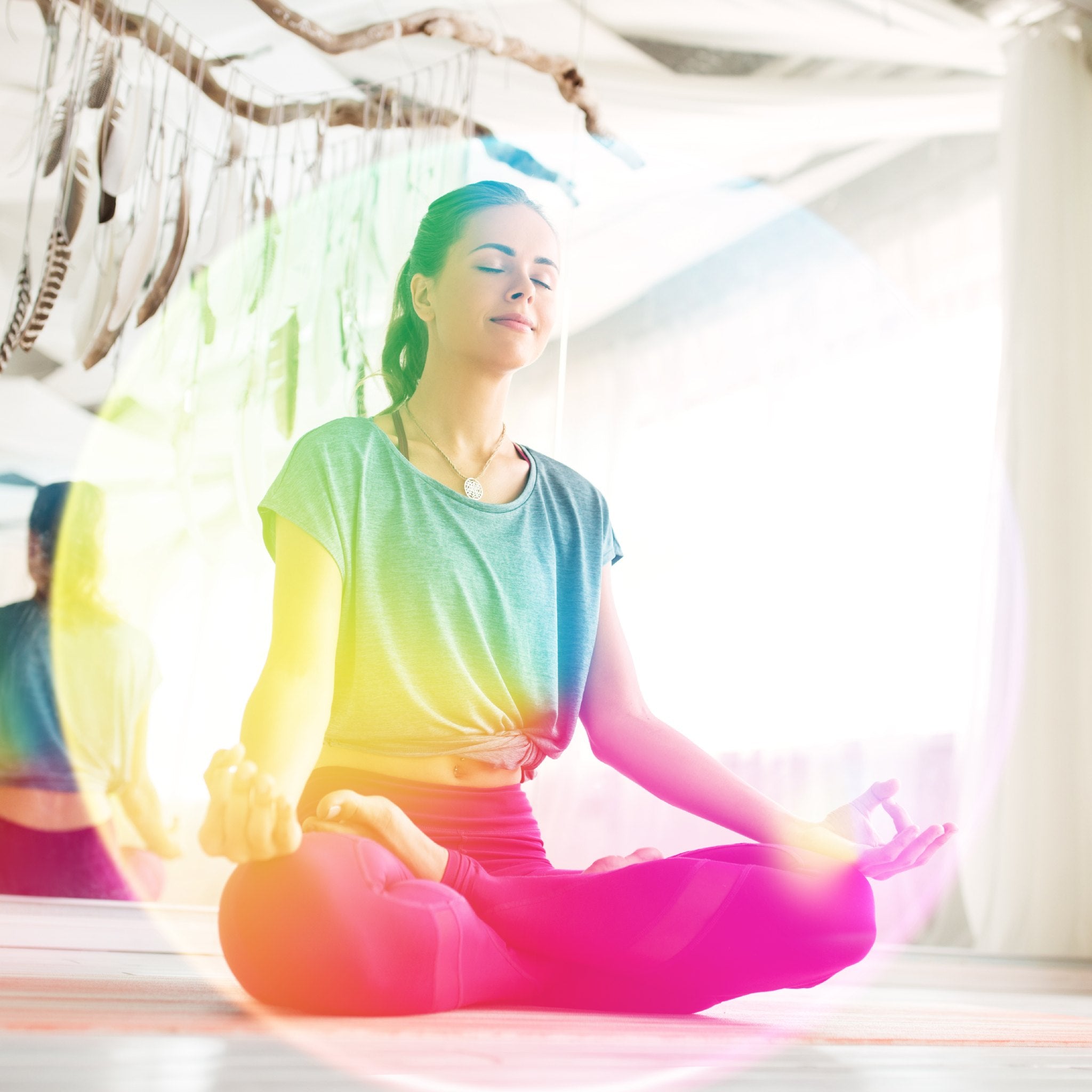 A woman meditating in the lotus pose, surrounded by a swirling rainbow for aura purification.
