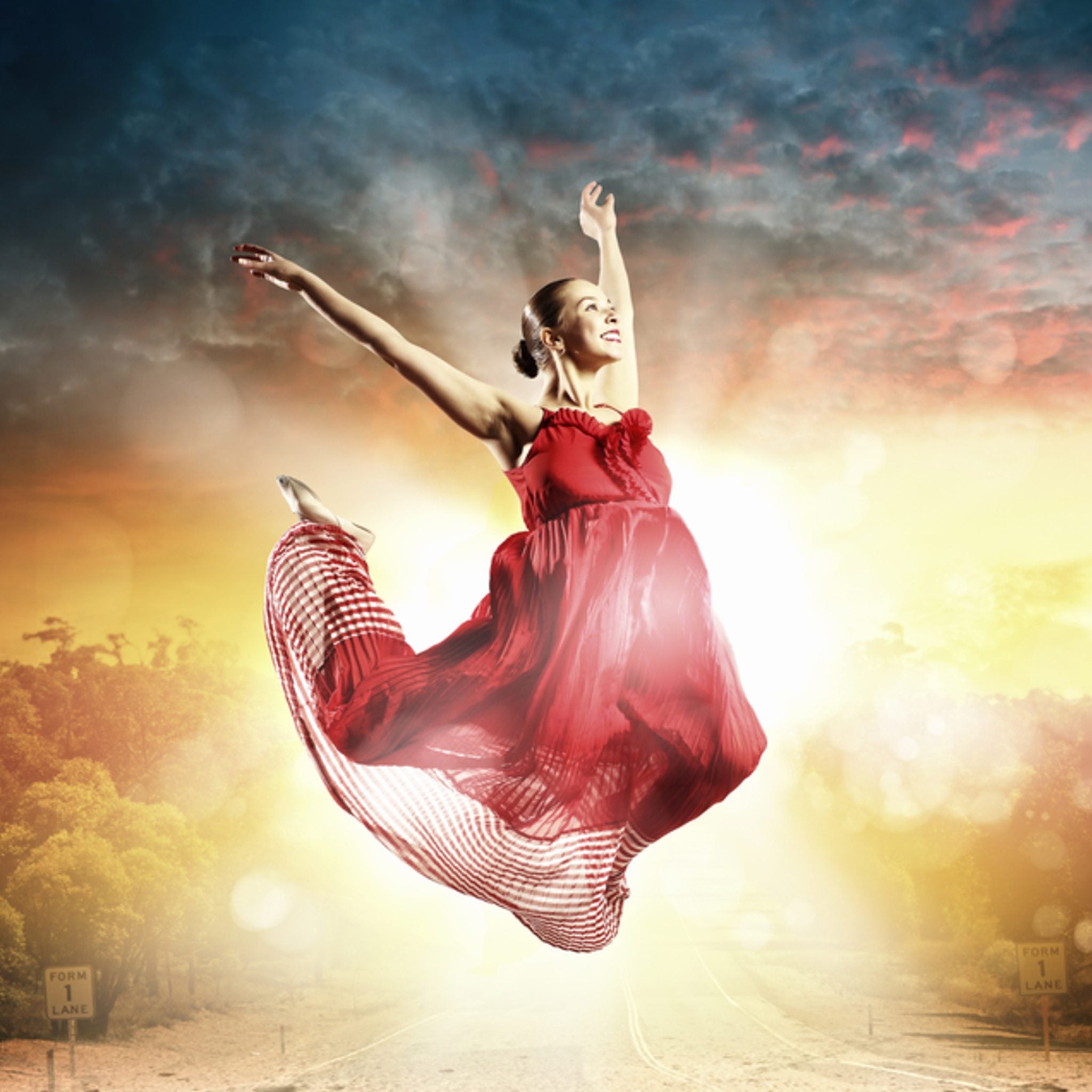 Smiling dancer in a bright red dress performing against a dramatic sky symbolising freedom.