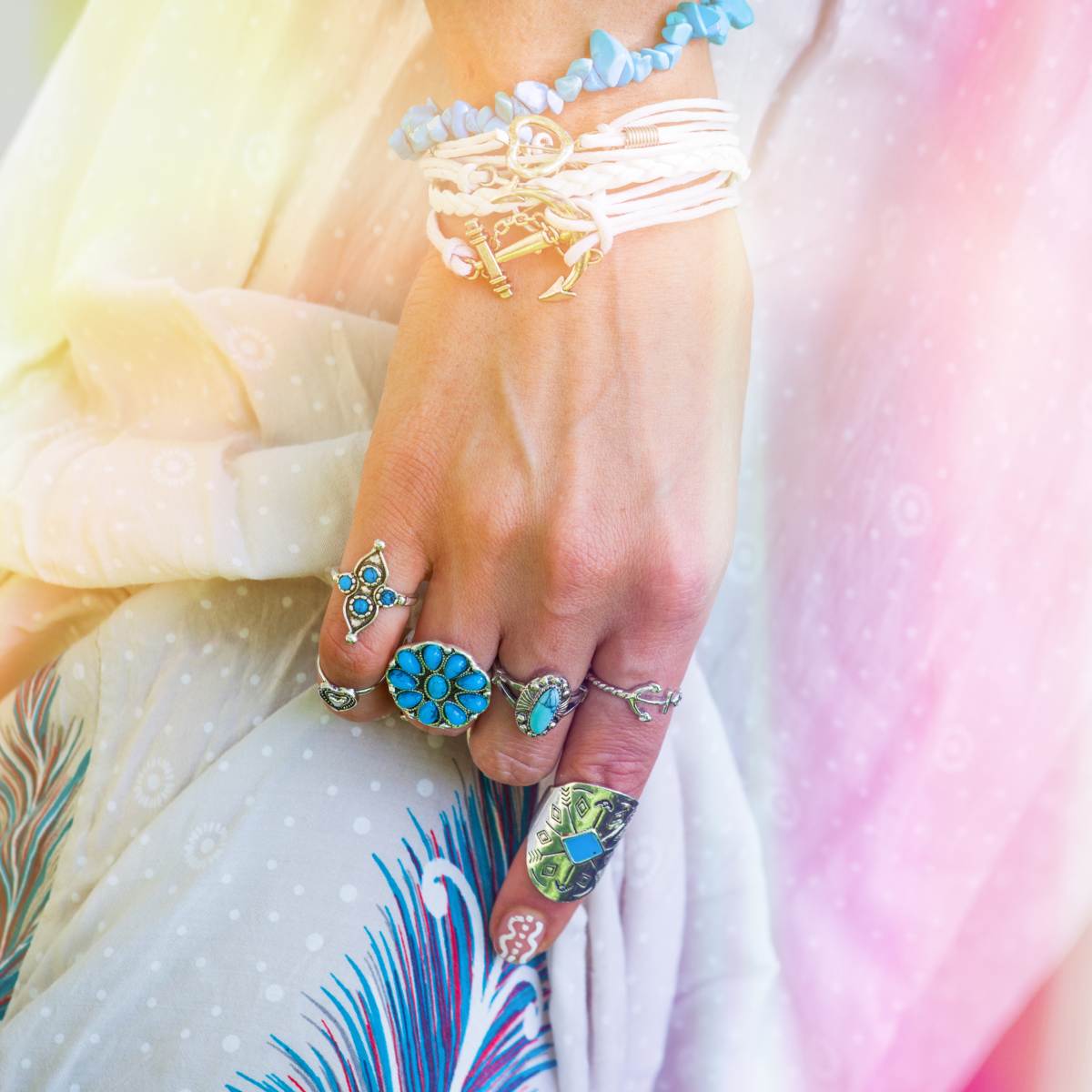 Hand with multiple rings on a colourful fabric background with beautiful light energy.