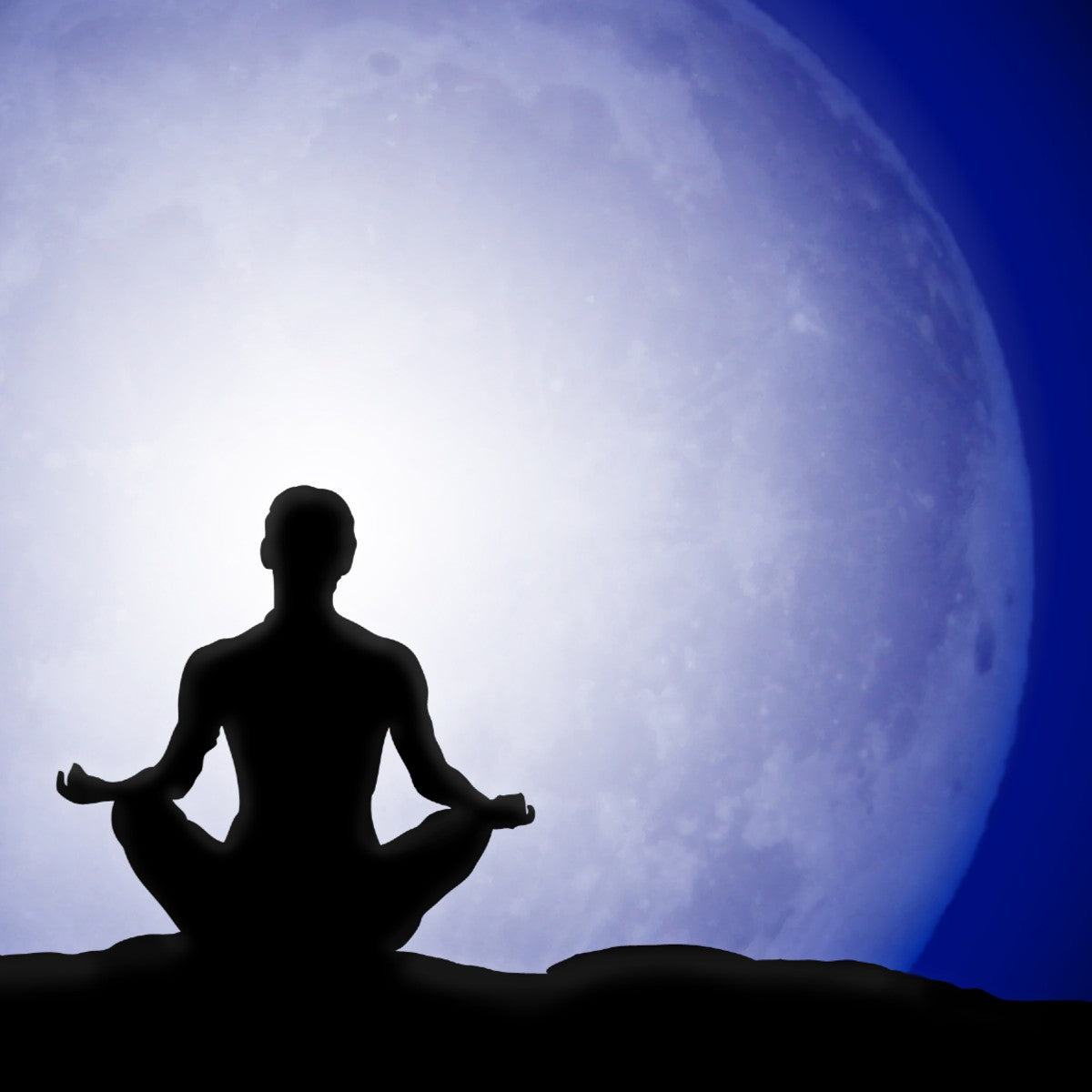 Silhouette of a person meditating in lotus pose against a large glowing full moon on a dark blue night sky.