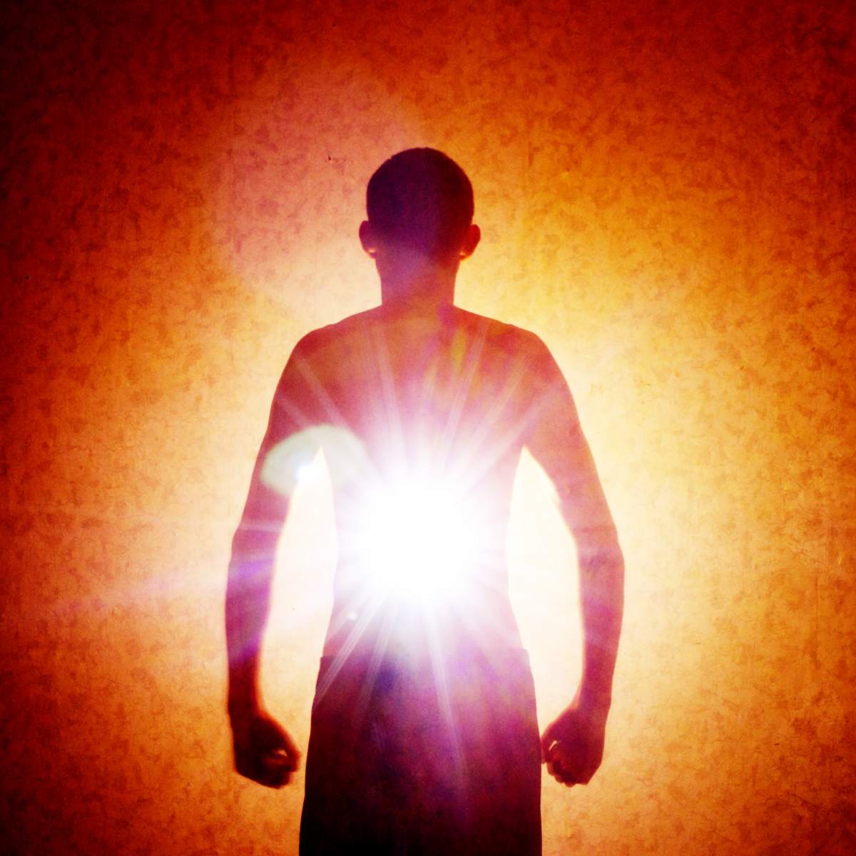 Silhouette of a person against a bright light source with a textured orange background.