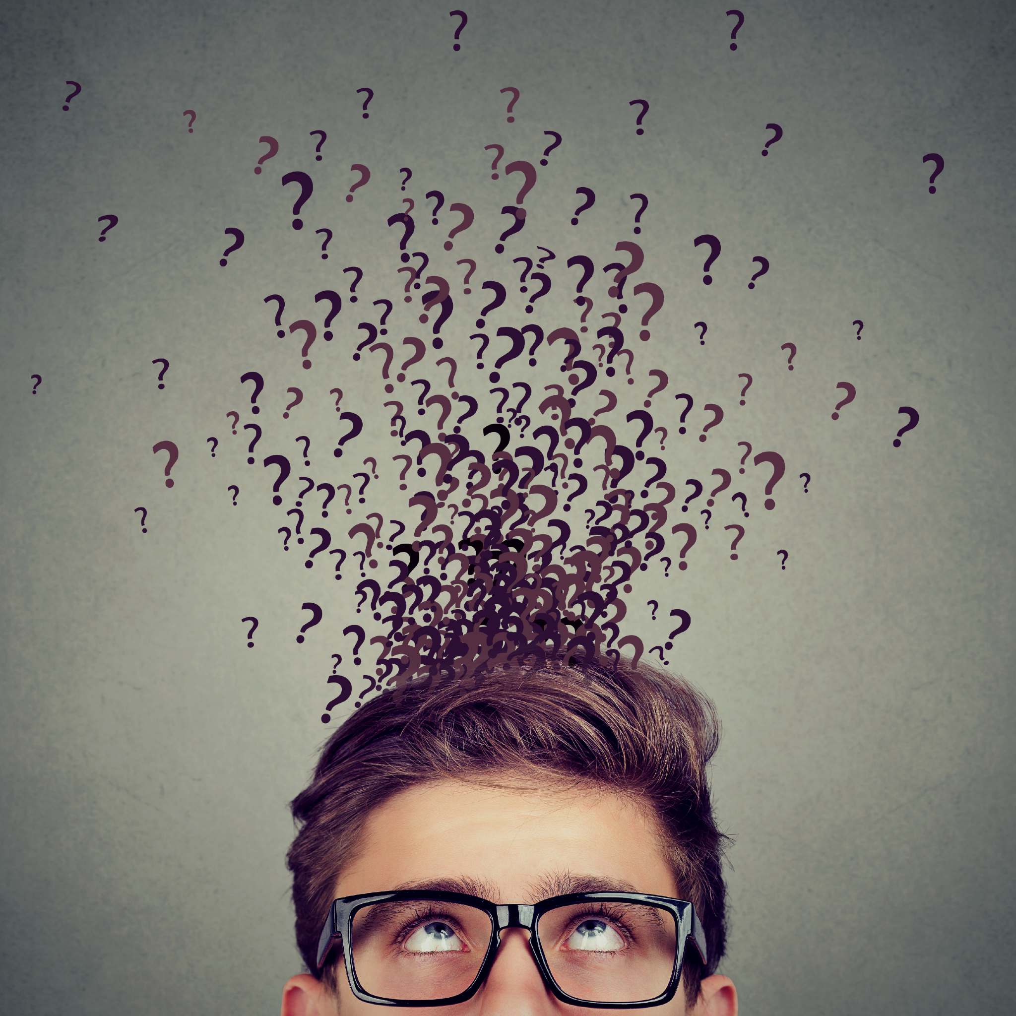 A man in glasses looking up, surrounded by many question marks above his head, signifying the curiosity rite.