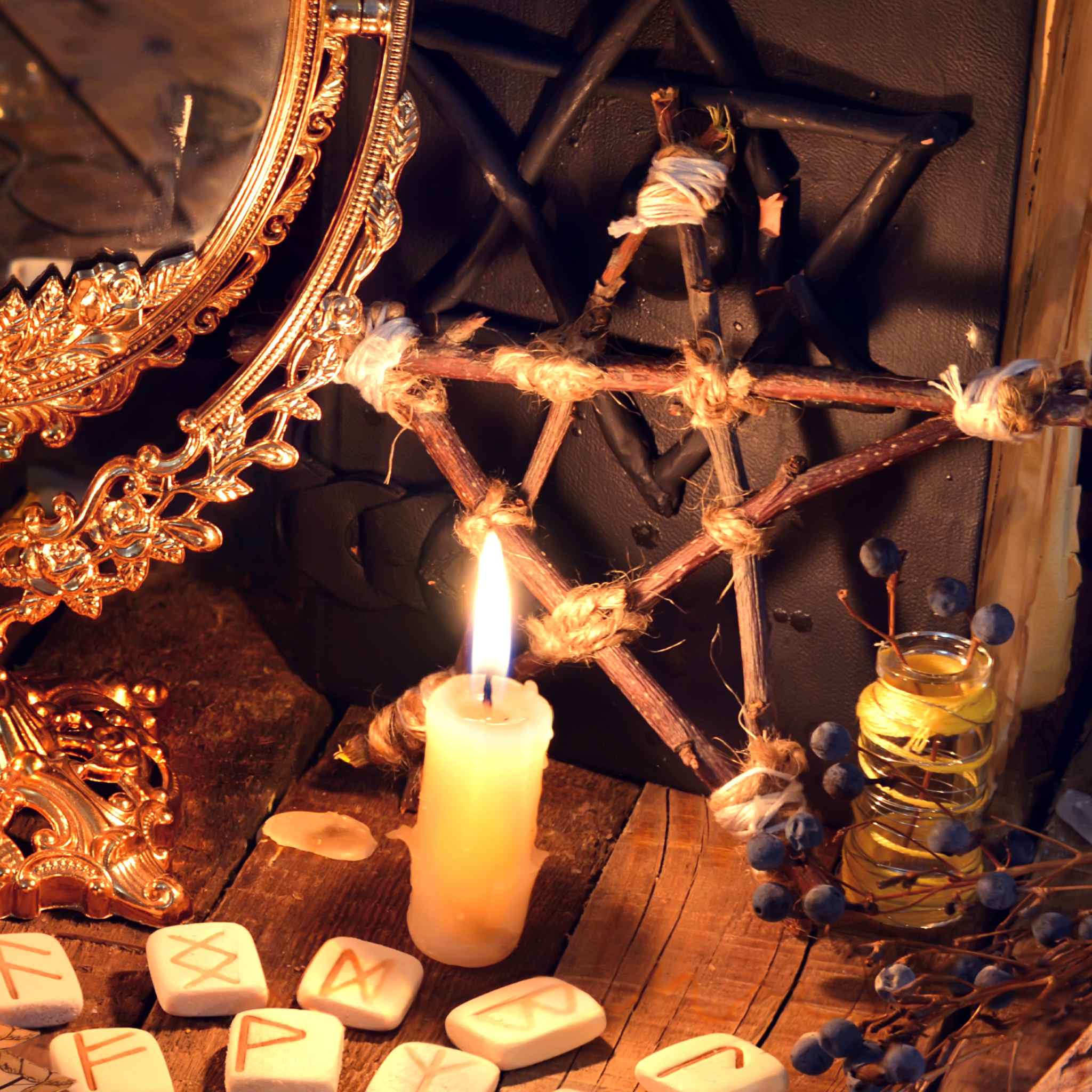 Protection objects on a table with a pentagram, candles, and runes on a wooden surface.
