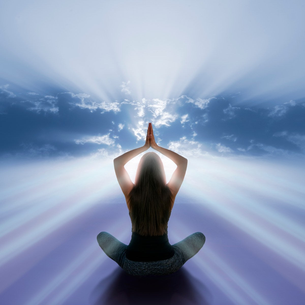 Person manifestation meditating with hands pressed together against a bright sky.