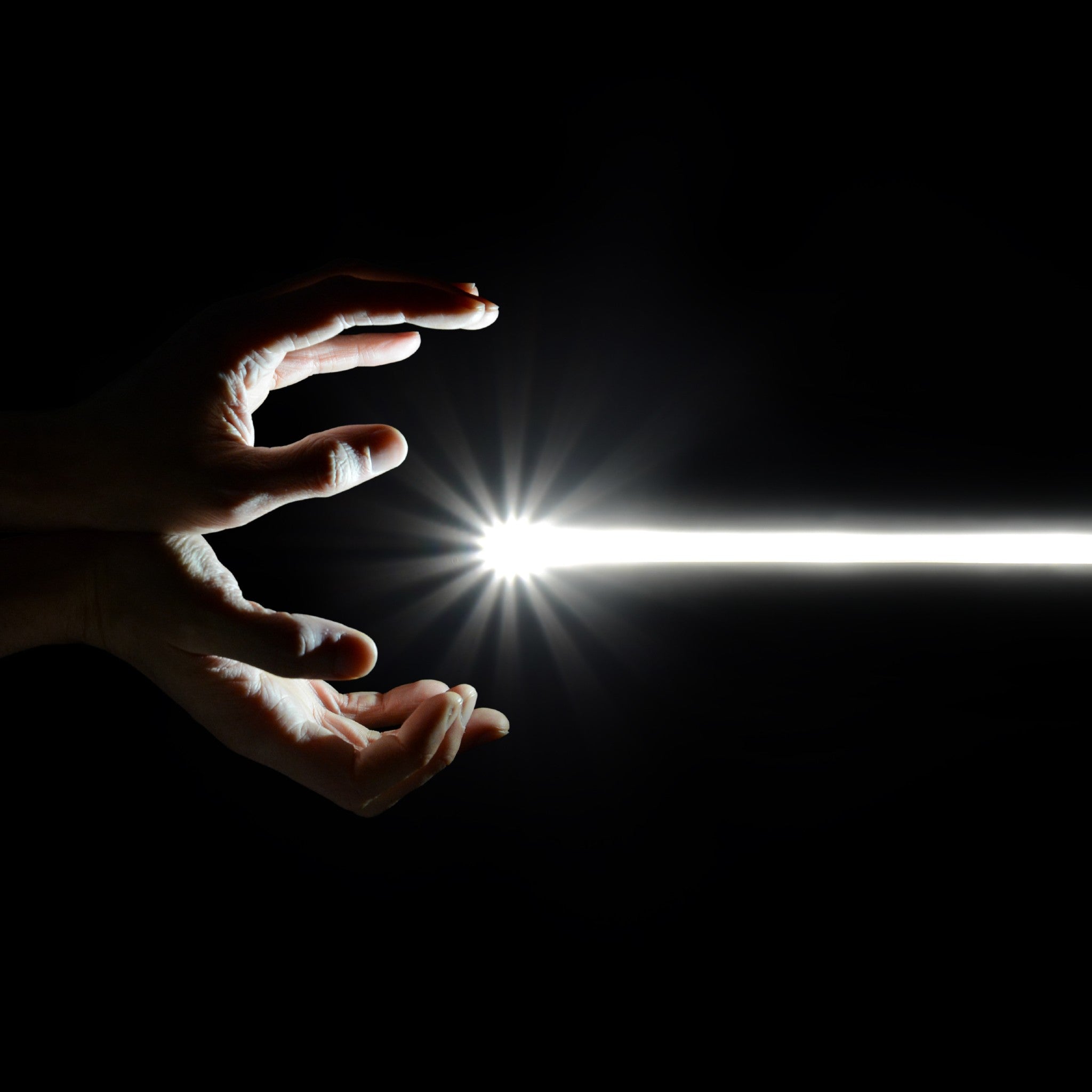 A pair of hands in the dark appear to be channeling or creating a single, intense beam of white light with a starburst effect, symbolising a focused, high-speed energy transfer.