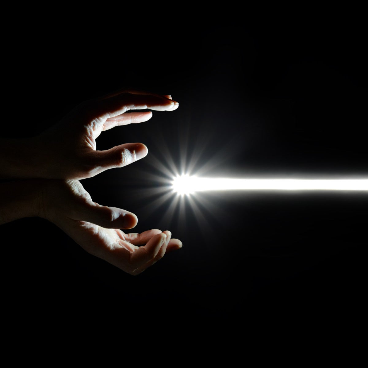 Two hands radiating a bright light source on a black background.
