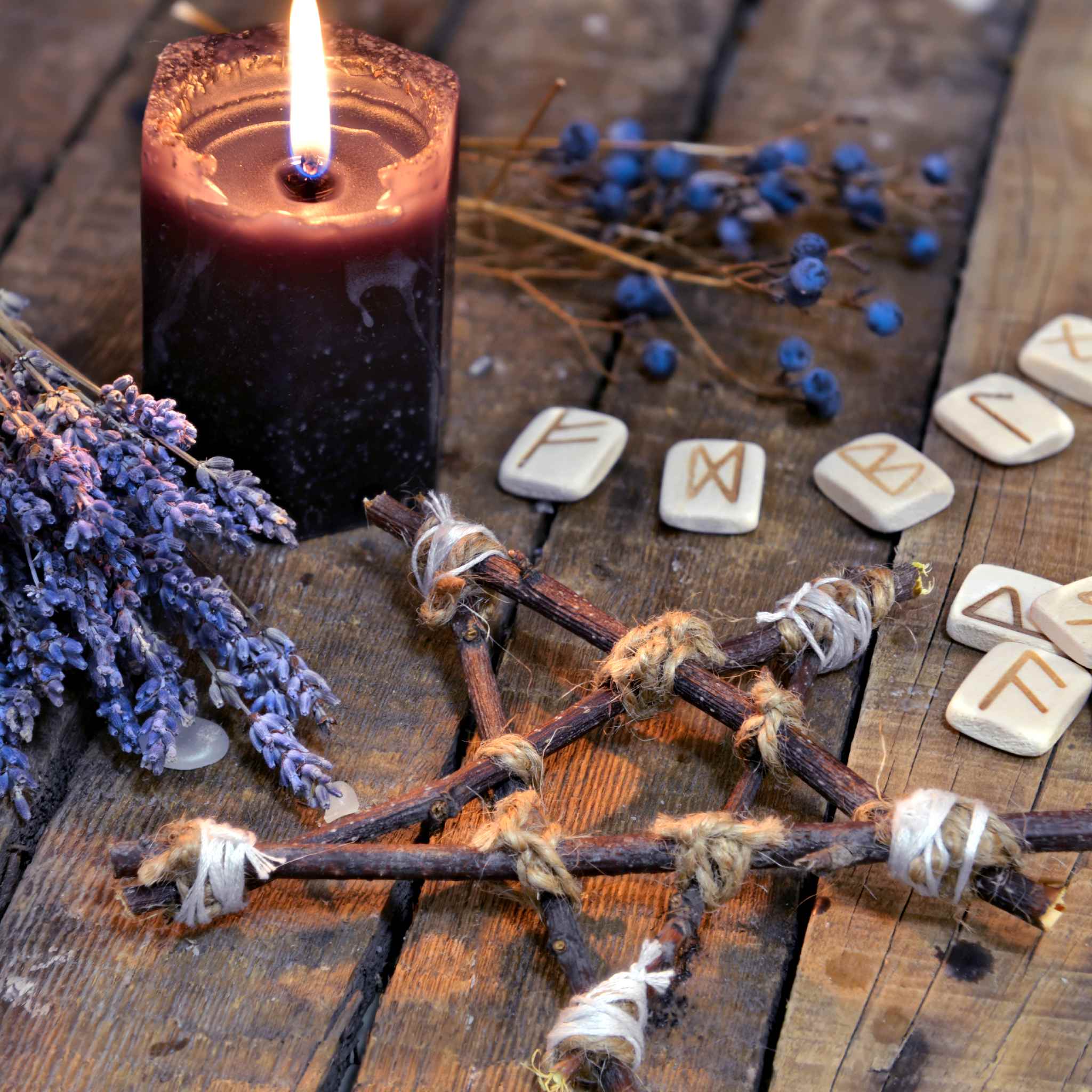 Candle, lavender, and spiritual and energy healing protection tools on a wooden surface.