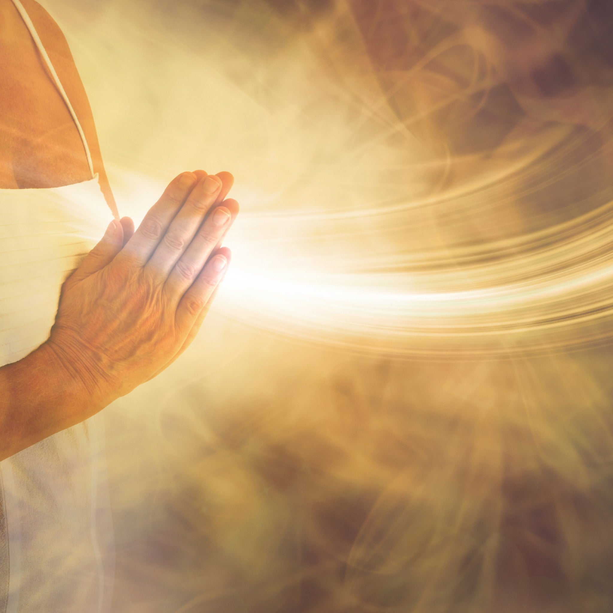 A close-up of hands held in prayer, palms glowing with intense golden light, symbolising the focused channel for the energy flow rite.