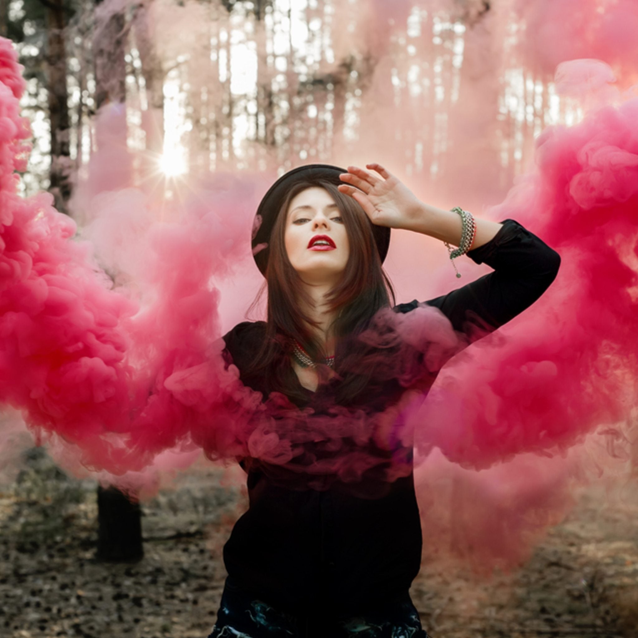 Energy Vampire Protection Maintenance Attunement: a woman in a dark hat and clothing surrounded by dense, swirling, bright pink smoke/fog in a forest setting.