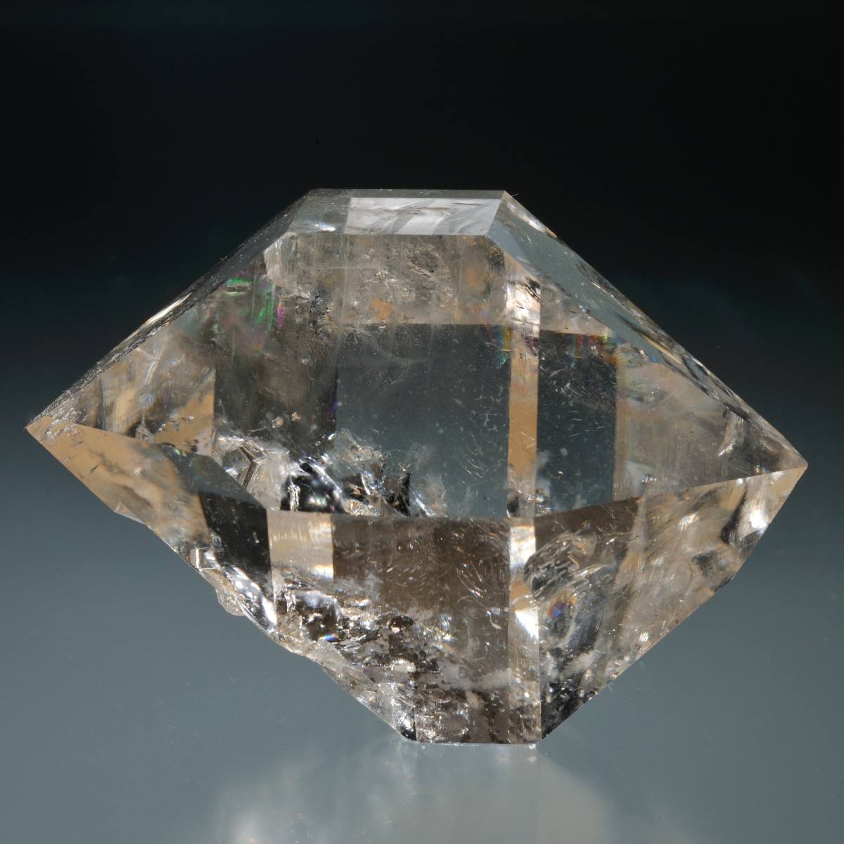 Clear herkimer diamond crystal with geometric shape on a dark background.