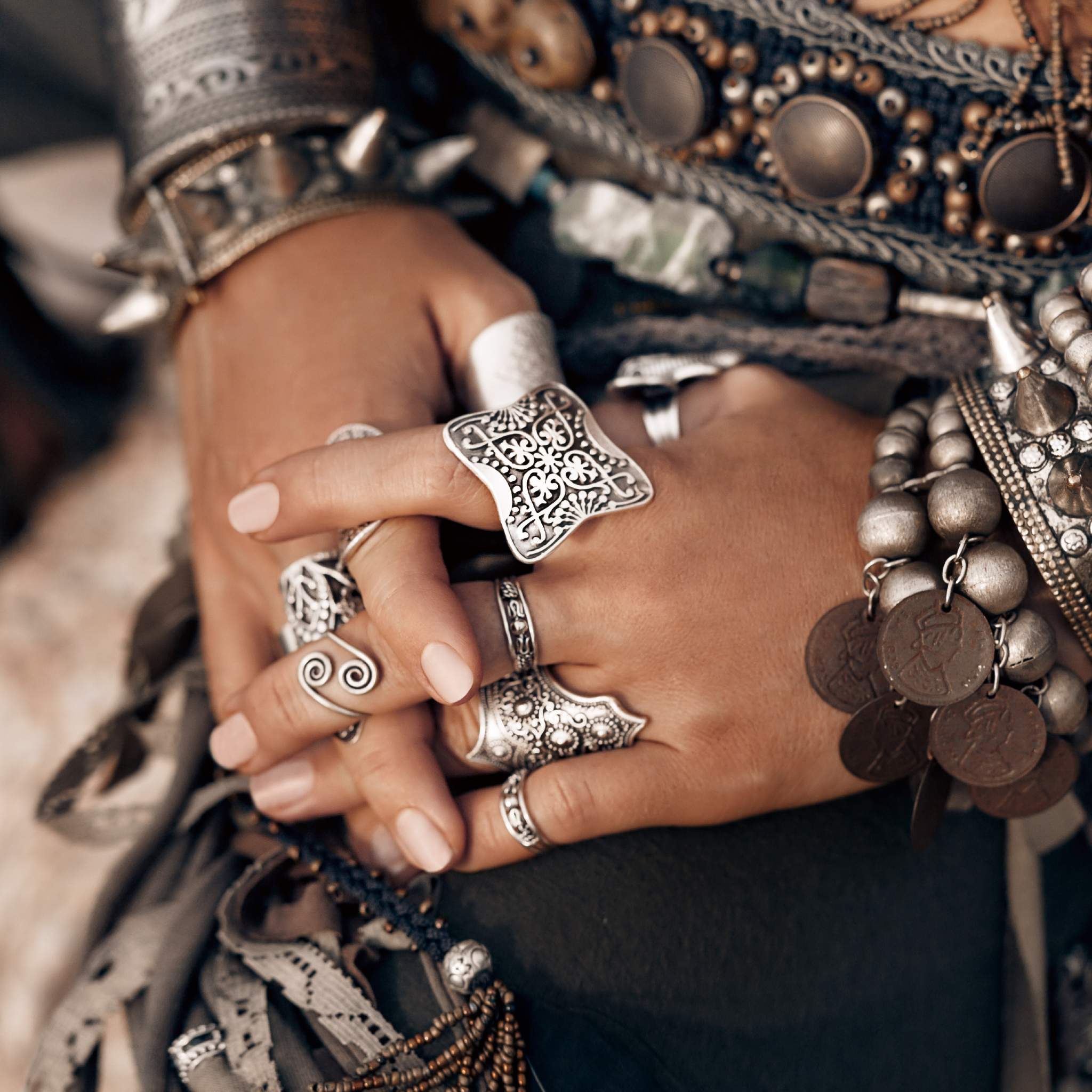 Close-up of hands wearing multiple silver rings and bracelets with intricate designs.