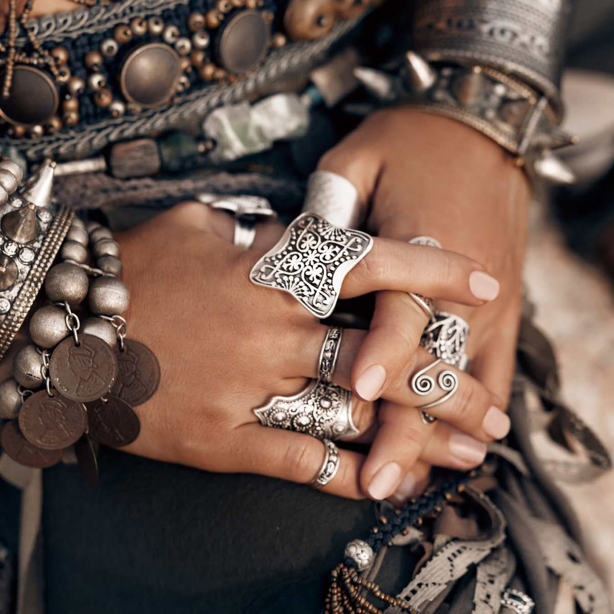 Close-up of hands wearing multiple silver rings and bracelets with intricate designs.