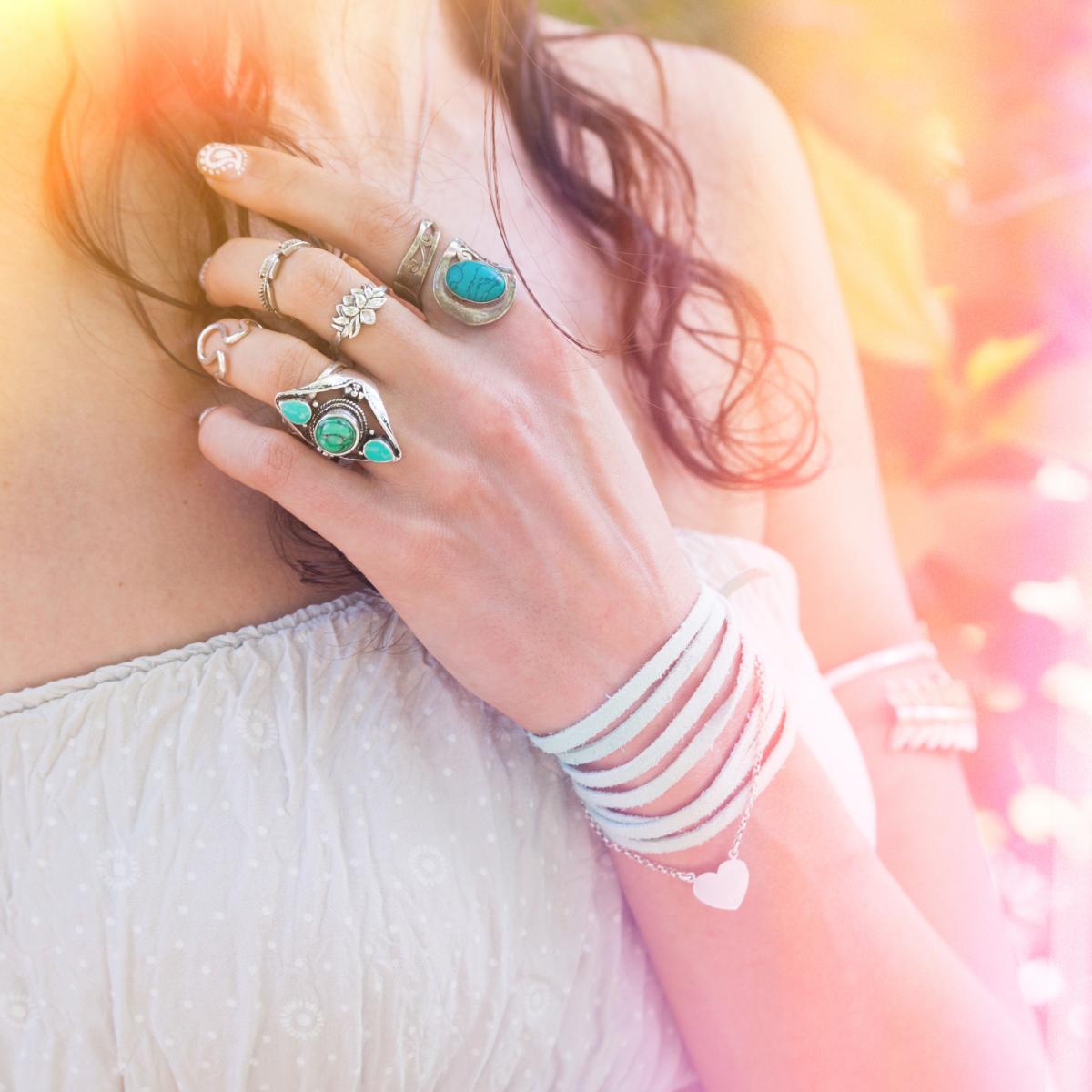 Close-up of a hand wearing multiple turquoise rings with a blurred background.