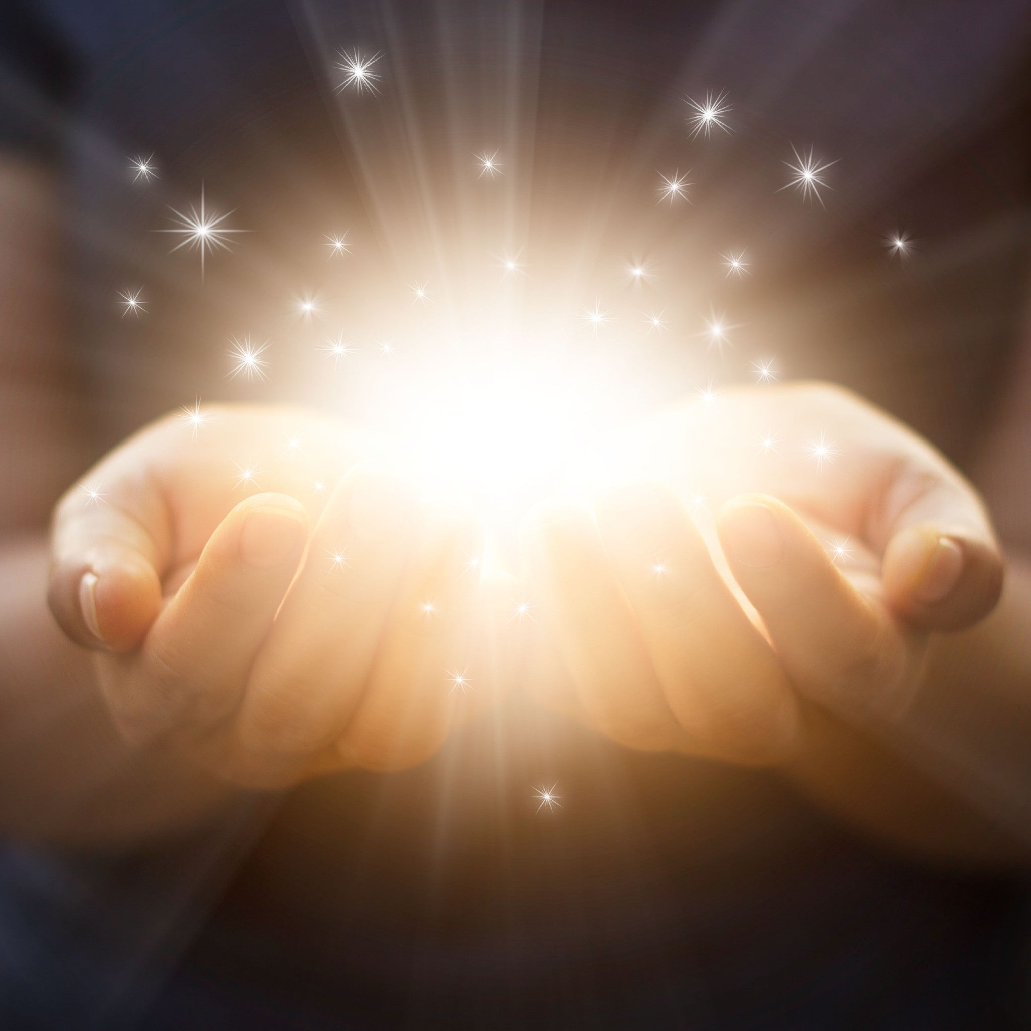 Two hands holding a bright light source with star-like sparkles on a dark background.