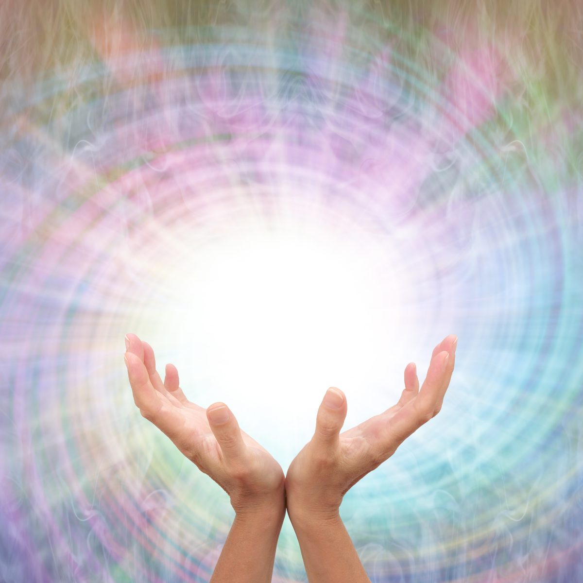 Hands reaching towards a bright Reiki light with a colourful, swirling background.