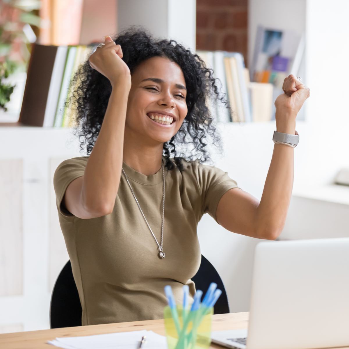 Woman with broad smile sitting at a desk in a bright office symbolising successful business.