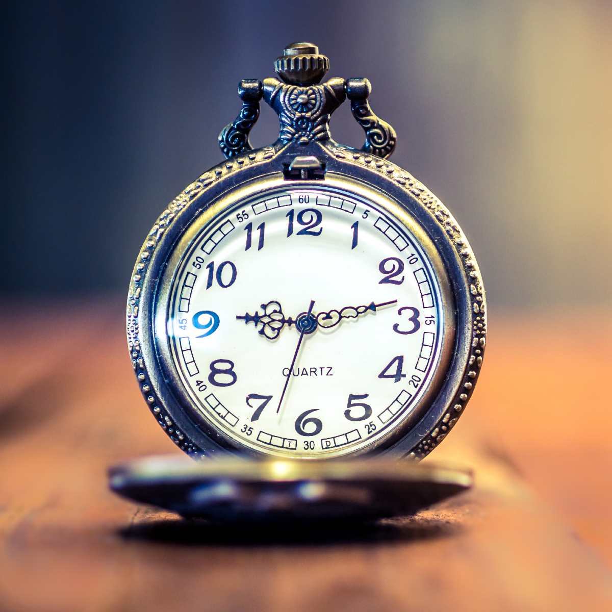 Vintage open pocket watch resting upright on a wooden surface.
