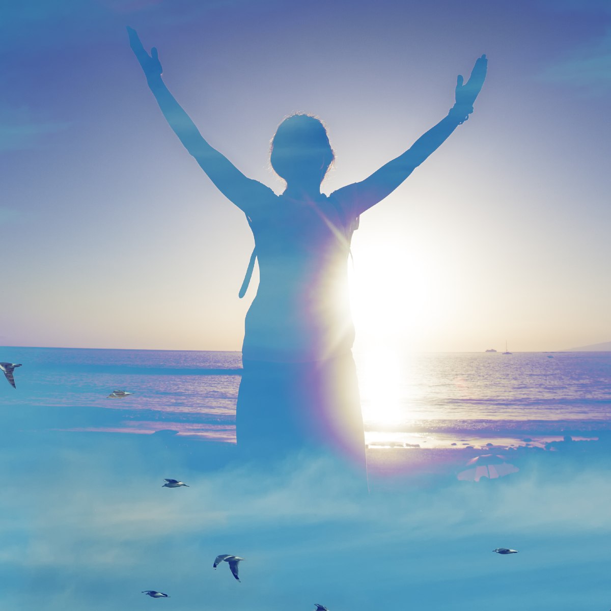 A person with arms raised, facing the setting sun with gratitude and celebration, on a beach at sunset with birds flying.