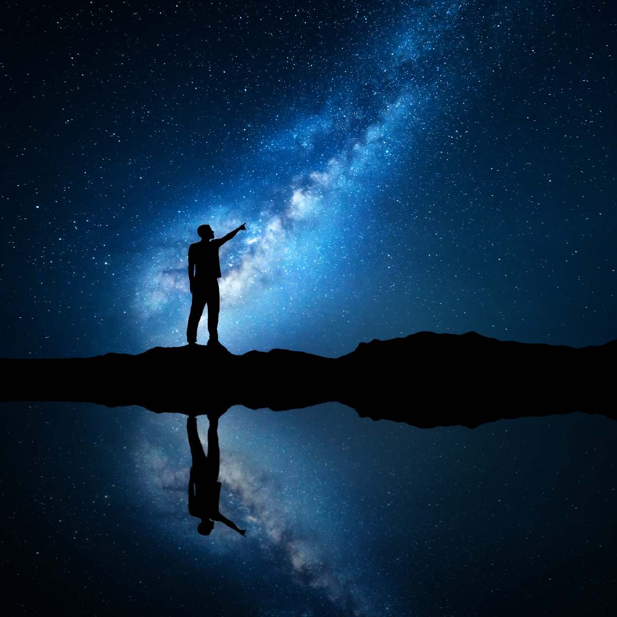 Person standing on a reflective surface pointing at the Milky Way galaxy representing past life reflection.