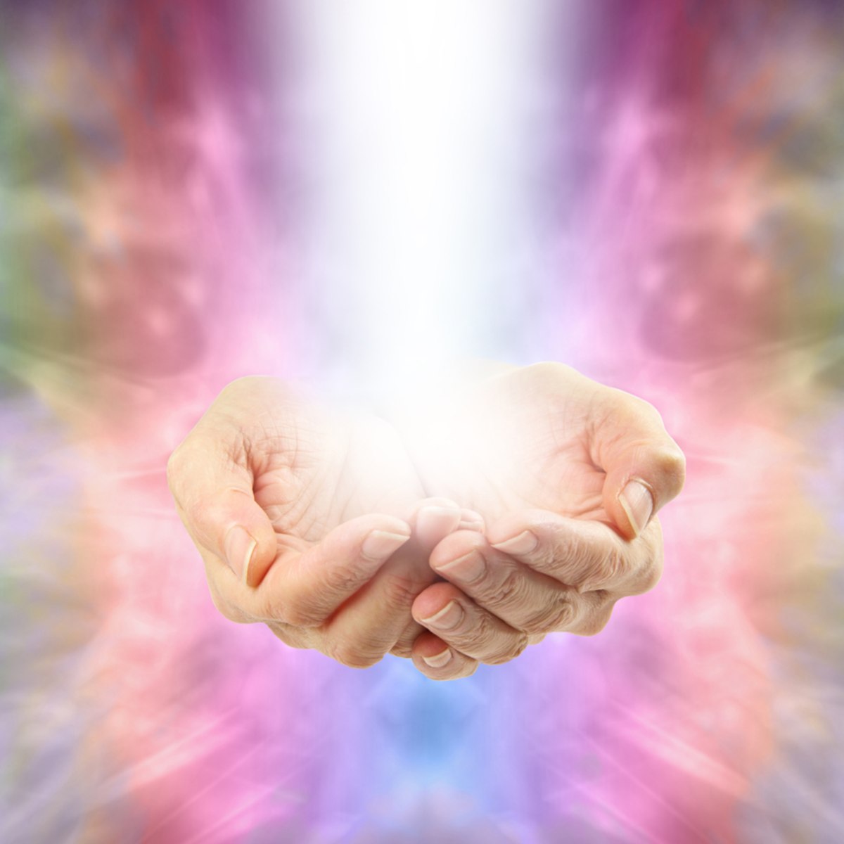 Two hands held together against a colourful, blurred Reiki energy background.