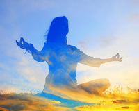 Silhouette of a person meditating on spiritual growth with a sunrise in the background.