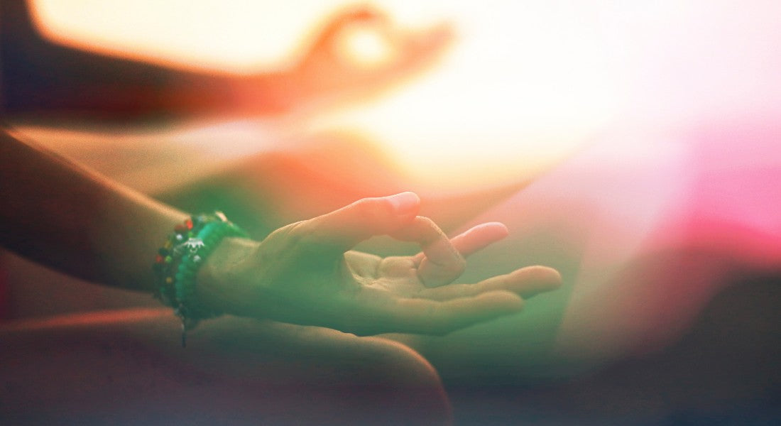 Two hands reaching towards each other with a blurred, warm light background.