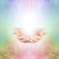 Two hands reaching towards each other against a soft Reiki energy background.
