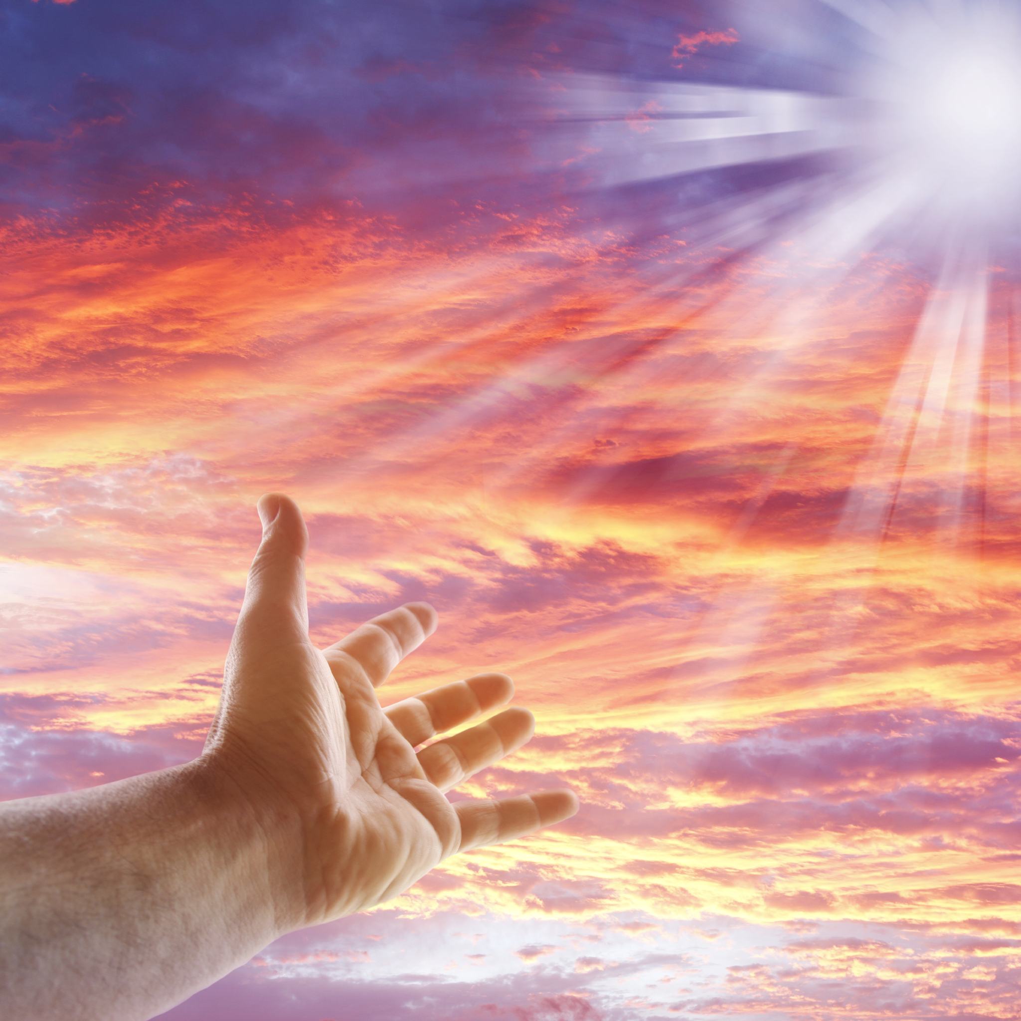 A hand reaches up toward a shining sunbeam breaking through a vibrant orange and pink cloudy sky, representing the ancestral rite.