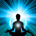 Silhouette of a meditating person with a bright light source behind them on a blue radiating background.