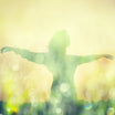 A person with arms wide open in a glowing, ethereal landscape, representing the spiritual freedom, expression, and empowerment of the attunement.