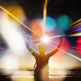Person with arms raised on a beach at sunset with colourful light and orb effects.