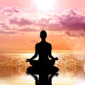 A beautiful silhouette of a person sitting in the lotus meditation pose on a calm body of water, with their reflection visible. The background is a vibrant sunset sky filled with pink and purple clouds over the horizon, representing the clarity and openness achieved through the blessing of authentic expression.