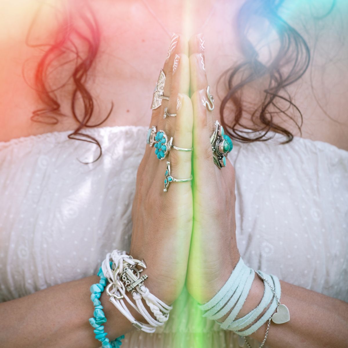 Close-up of a person's hands with multiple bracelets and rings on a white background.