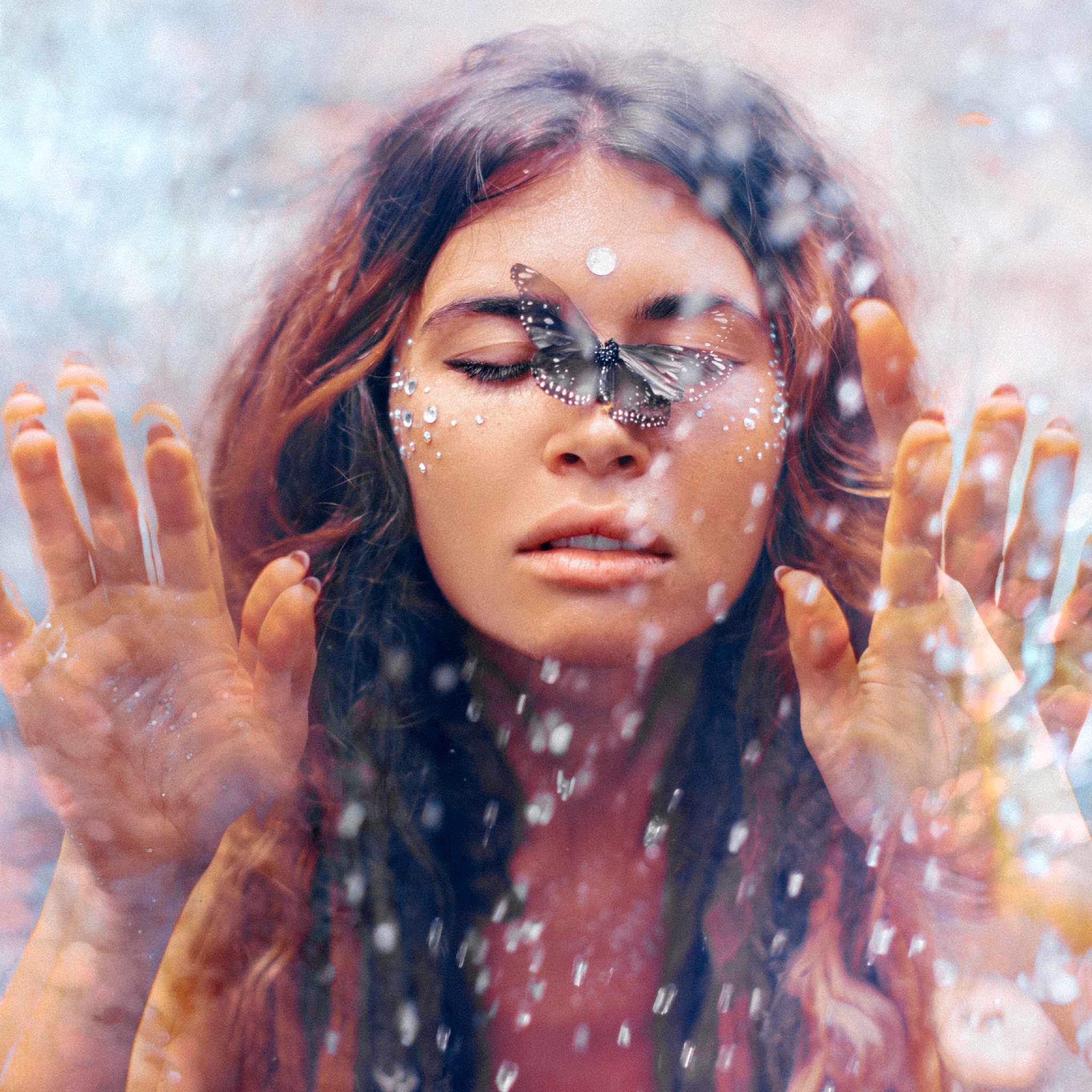 A beautiful woman with a small dark butterfly on her closed eyes, behind a wet glass pane, representing butterfly transmutation manifestation empowerment.