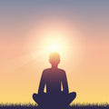 Silhouette of a person meditating with a sunset in the background.