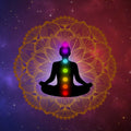 Silhouette of a person meditating with seven chakras against a starry background.