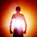 Silhouette of a person against a bright light source with a textured orange background.