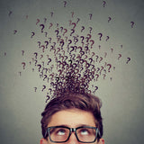 A man in glasses looking up, surrounded by many question marks above his head, signifying the curiosity rite.