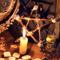 Protection objects on a table with a pentagram, candles, and runes on a wooden surface.